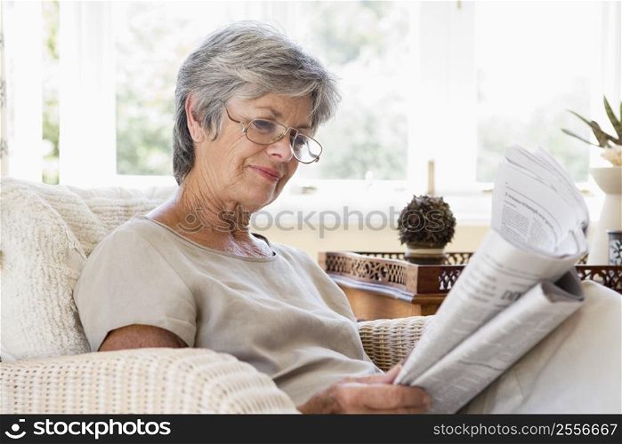 Woman in living room reading newspaper