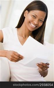 Woman in living room reading papers smiling