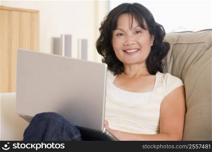 Woman in living room using laptop and smiling