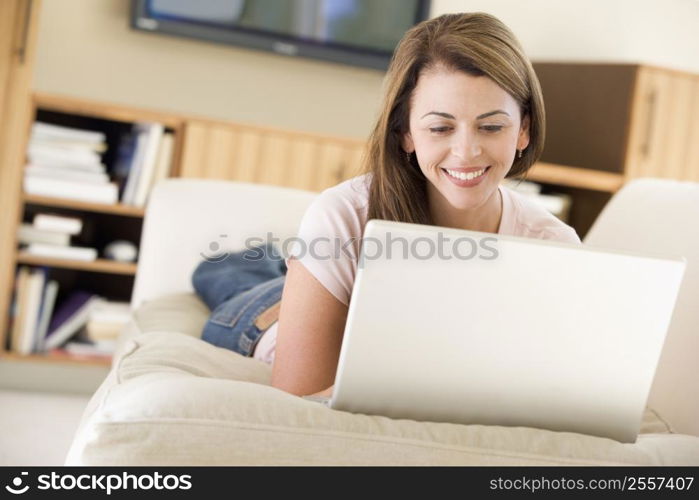 Woman in living room using laptop smiling