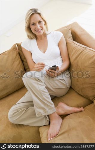 Woman in living room using personal digital assistant smiling