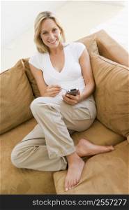 Woman in living room using personal digital assistant smiling