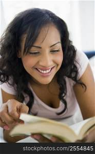Woman in living room with book smiling (high key/selective focus)