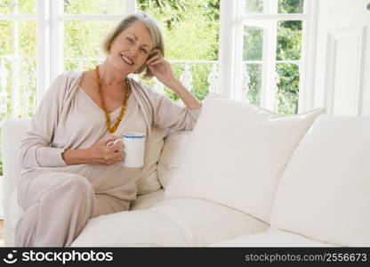 Woman in living room with coffee smiling