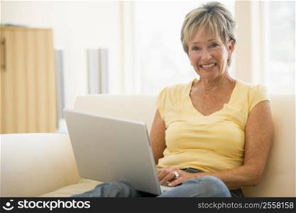 Woman in living room with laptop smiling