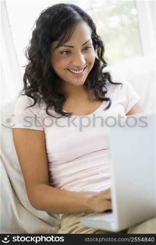 Woman in living room with laptop smiling (high key/selective focus)