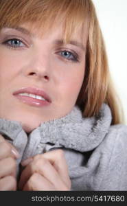 Woman in makeup and a snug grey hooded sweatshirt