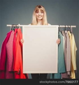 Woman in mall wardrobe with blank banner copyspace. Happy smiling pretty woman in wardrobe holding blank empty banner. Gorgeous girl customer in mall shop with copyspace. Fashion clothing sale advertisement concept. Instagram filter.