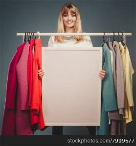 Woman in mall wardrobe with blank banner copyspace. Happy smiling pretty woman in wardrobe holding blank empty banner. Gorgeous girl customer in mall shop with copyspace. Fashion clothing sale advertisement concept. Instagram filter.
