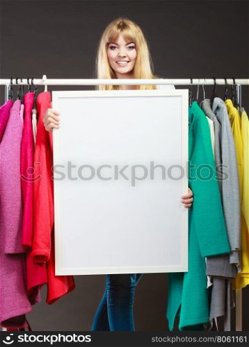 Woman in mall wardrobe with blank banner copyspace. Woman in wardrobe holding blank empty banner. Girl customer in mall shop with copyspace. Fashion clothing sale advertisement.