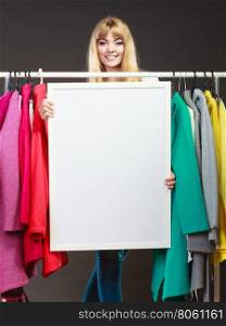 Woman in mall wardrobe with blank banner copyspace. Woman in wardrobe holding blank empty banner. Girl customer in mall shop with copyspace. Fashion clothing sale advertisement.