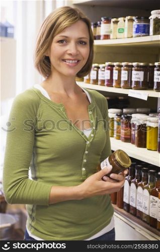 Woman in market looking at preserves smiling