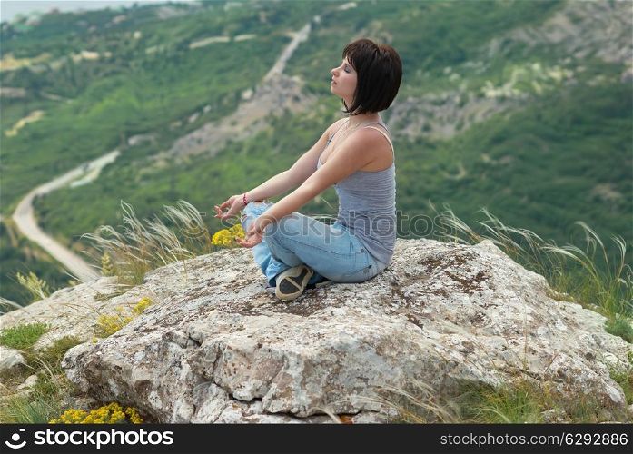 Woman in meditation, relaxing on the rock