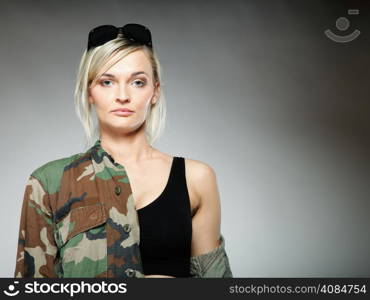 woman in military clothes with sunglasses army girl on gray background.