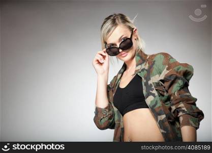 woman in military clothes with sunglasses army girl on gray background.
