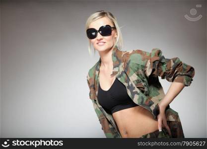 woman in military clothes with sunglasses army girl on gray background.