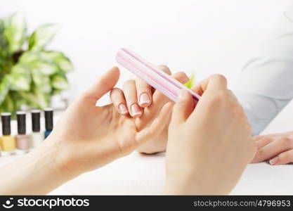 Woman in nail salon receiving manicure by beautician