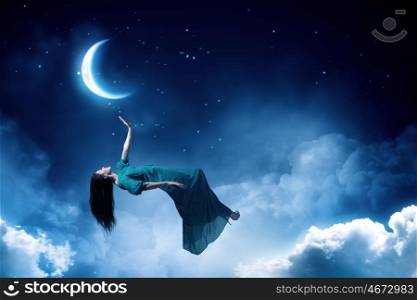 Woman in night sky. Elegant woman in green long dress floating in night sky