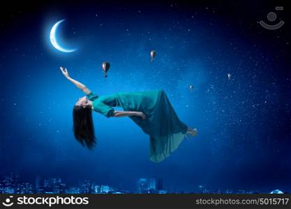 Woman in night sky. Elegant woman in green long dress floating in night sky