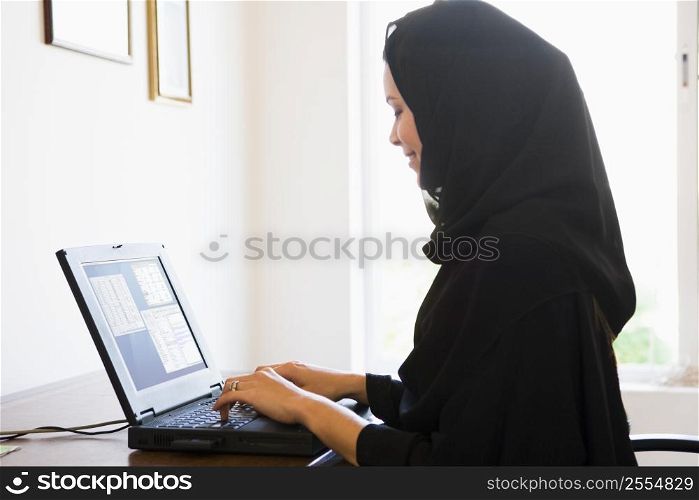 Woman in office with laptop smiling (high key/selective focus)
