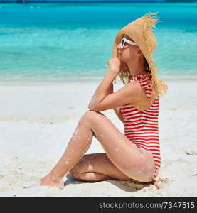 Woman in one-piece swimsuit at tropical beach with white sand. Summer vacation at Maldives.