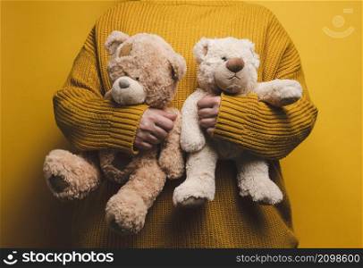woman in orange knitted sweater hugs cute brown teddy bear. The concept of loneliness and sadness, depression