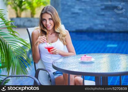 Woman in outdoor cafe. Beautiful woman sitting in outdoor cafe with cocktail and cake enjoying summer tropical vacation