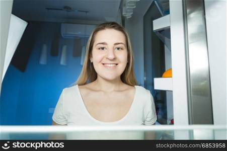 Woman in pajamas looking inside the refrigerator at home at late night