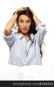 woman in pajamas sitting in bed holding her hair. woman in pajamas sitting in bed holding her hair on white background