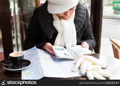 Woman in Paris at a map while having a coffee