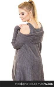 Woman in ponytail wearing gray long top sweater tunic with holes on shoulders. Stylish, autumnal outfit.. Woman wearing gray long top sweater tunic