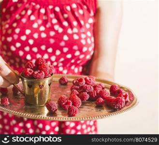 Woman in red dress holding a cup of raspberries