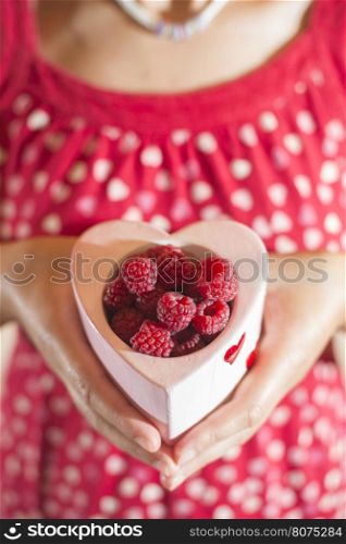 Woman in red dress holding a cup of raspberries