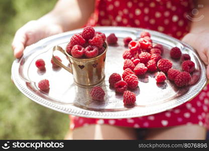 Woman in red dress holding a cup of raspberries