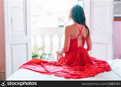 Woman in red dress in her apartments in old Havana at Cuba. Young attractive woman in red dress on old balcony in apartment in Havana
