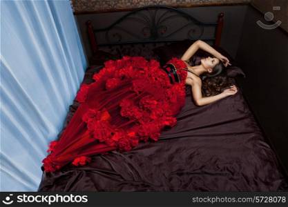 Woman in red dress on the bed in the interior