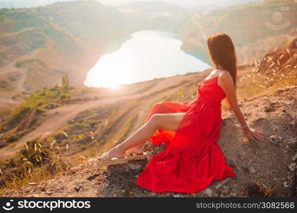 Woman in red dress standing near the lake like heart. Concept of european vacation. Beautiful landscape. Mother near the lake at the day time.