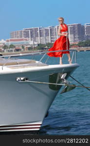 woman in red dress stood on bow of boat