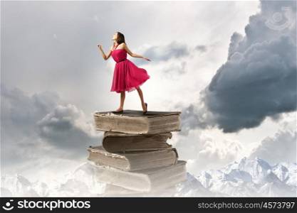 Woman in red dress. Young woman in red dress standing on pile of books