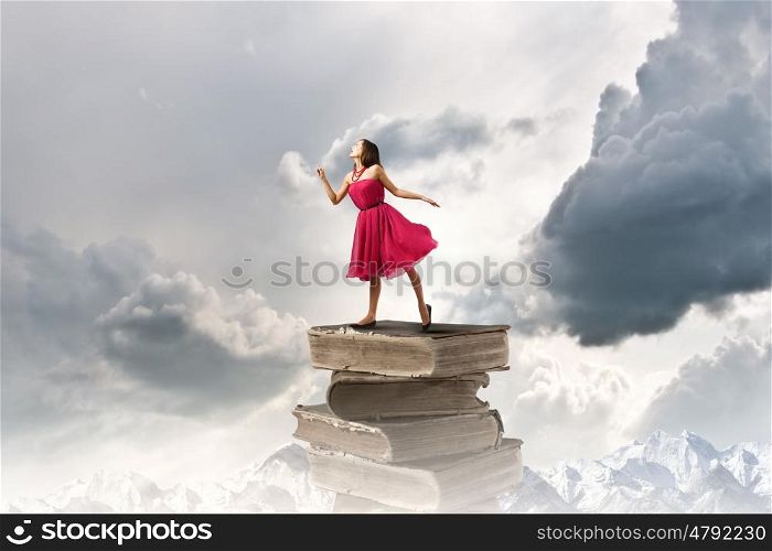 Woman in red dress. Young woman in red dress standing on pile of books