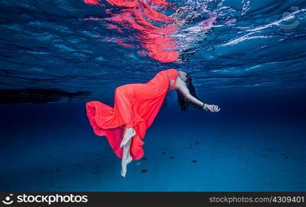 Woman in red floating near surface of ocean