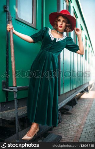 Woman in red hat against old railway wagon. Retro train. Railroad journey. Woman in red hat against old railway wagon