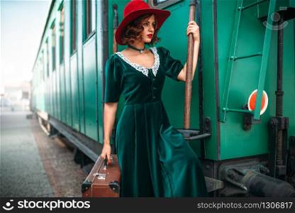 Woman in red hat against old railway wagon. Retro train. Railroad journey