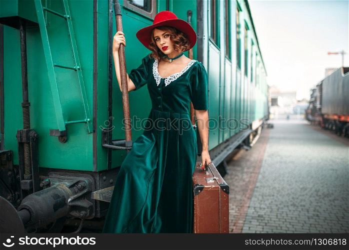 Woman in red hat against old railway wagon. Retro train. Railroad journey. Woman in red hat against old railway wagon