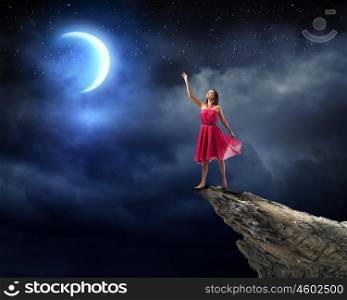 Woman in red. Young attractive woman in red dress standing on rock edge