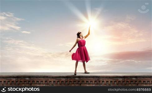 Woman in red. Young attractive woman in red dress touching light spot