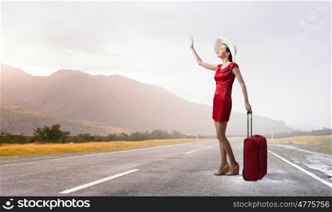 Woman in red. Young woman in red dress on road with red luggage