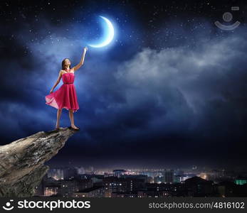 Woman in red. Young woman in red dress standing on edge of rock