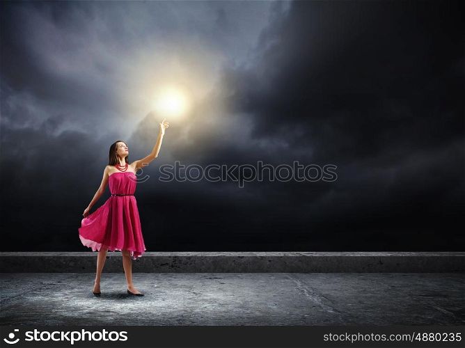 Woman in red. Young woman in red dress touching light spot