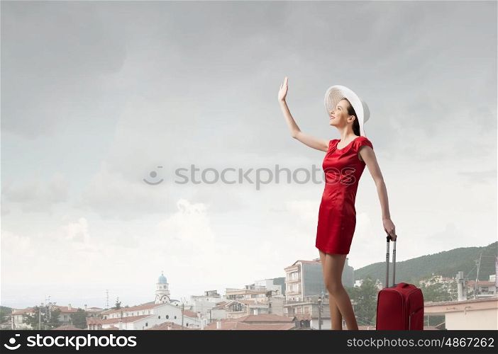 Woman in red. Young woman in red dress with red luggage gesturing with hand